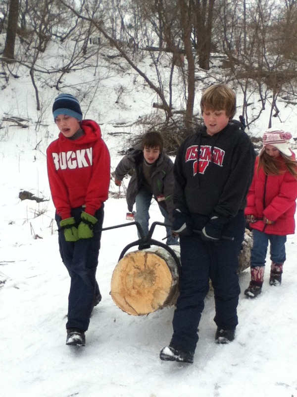 Four students using calipers to carry large log